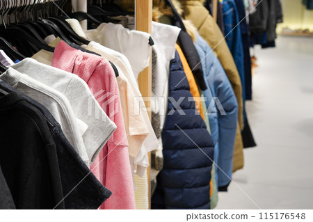 A rack of various clothes including t-shirts, jackets, and sweaters in different colors and materials A rack of various clothes including t-shirts, jackets, and sweaters in different colors and materials 115176548