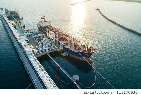 Aerial view of a large oil tanker docked at a pier in the port in process of loading. Aerial view of a large oil tanker docked at a pier in the port in process of loading. 115176636