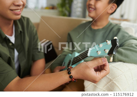 Helping Son to Tune Ukulele Helping Son to Tune Ukulele 115176912