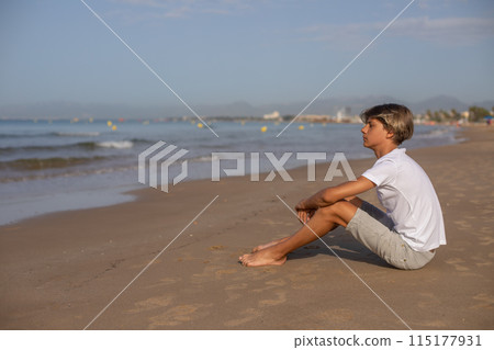 Handsome teenager boy sitting at the beach and enjoy a summer vacation. Handsome teenager boy sitting at the beach and enjoy a summer vacation. 115177931