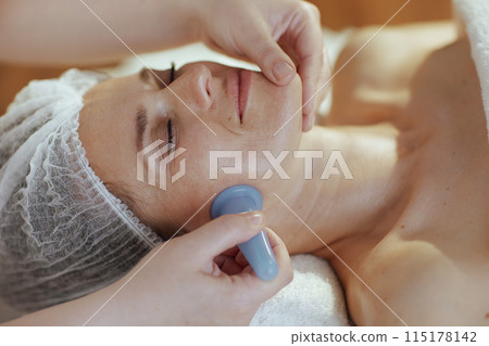 medical massage therapist massaging clients face 115178142