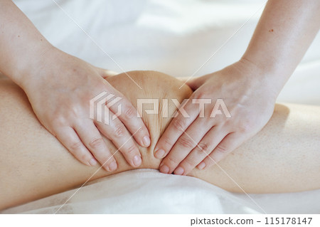 Closeup on massage therapist in spa salon massaging clients leg Closeup on massage therapist in spa salon massaging clients leg 115178147