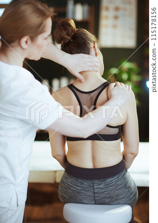 massage therapist checking clients neck condition during checkup massage therapist checking clients neck condition during checkup 115178156