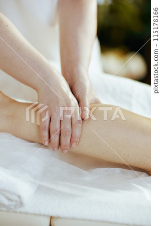 Closeup on medical massage therapist massaging clients leg 115178166