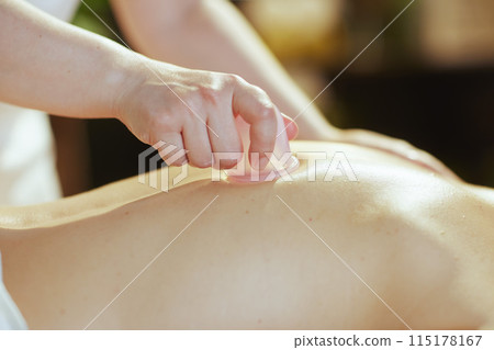 Closeup on medical massage therapist massaging clients back 115178167
