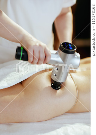 Massage therapist in massage cabinet massaging clients buttocks 115178168