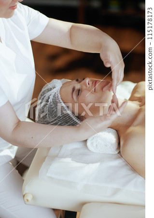 massage therapist in spa salon massaging clients face 115178173