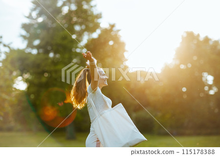 smiling stylish female in white shirt with tote bag rejoicing 115178388