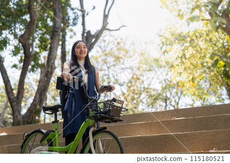 Smiling Asian woman with bicycle outdoors. Concept of eco friendly commuting Smiling Asian woman with bicycle outdoors. Concept of eco friendly commuting 115180521