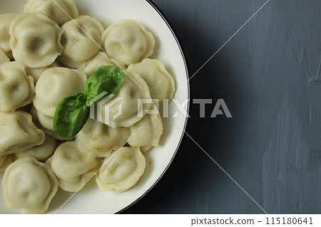 Cooked boiled dumplings in a bowl of basil greens top view close-up on a gray background with space for text copyspace Cooked boiled dumplings in a bowl of basil greens top view close-up on a gray background with space for text copyspace 115180641