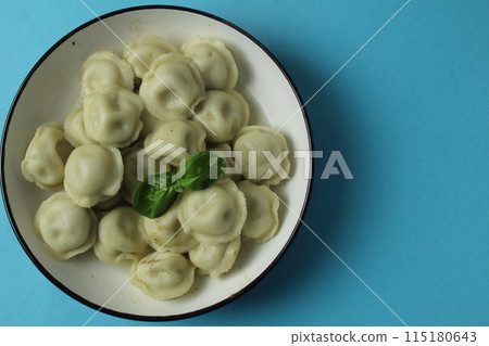 Dumplings in a plate with basil greens on a blue background with space for copyspace text. The concept of Slavic food Dumplings in a plate with basil greens on a blue background with space for copyspace text. The concept of Slavic food 115180643