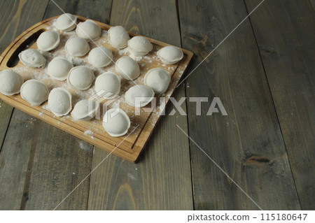 Frozen dumplings on a wooden board on a gray background with space for copyspace text for filling dough recipe. Slavic German traditions. Quick lunch Frozen dumplings on a wooden board on a gray background with space for copyspace text for filling dough recipe. Slavic German traditions. Quick lunch 115180647