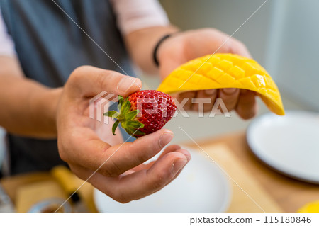 Chef at the kitchen preparing bowl of oats with strawberries and mango 115180846