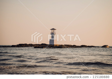 Lighthouse surrounded by water and cloudy sunset sky 115180880