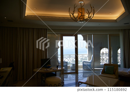 RAS AL KHAIMAH, UNITED ARAB EMIRATES - JUN 11, 2019: Luxurious hotel room with view from the living area to the large balcony in a five star hotel 115180892