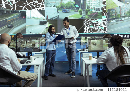 Indian team of operators instructing their colleagues to use CCTV surveillance footage and guide couriers in traffic. Employees operating with global positioning system in satellite map. Indian team of operators instructing their colleagues to use CCTV surveillance footage and guide couriers in traffic. Employees operating with global positioning system in satellite map. 115181011