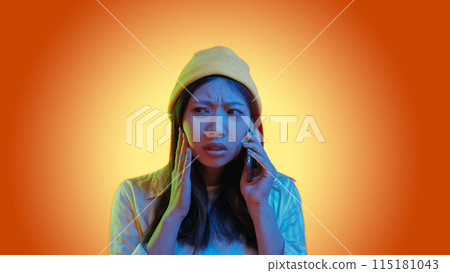 Disturbing call. Mobile scam. Blue color neon light scared confused woman speaking on phone isolated on orange gradient empty space background. 115181043