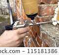 Window installation. The process of insulating windows with construction foam. A builder's hand seals the cracks between the building and the window frame. Construction and insulation of the building. 115181386