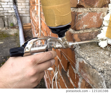 Window installation. The process of insulating windows with construction foam. A builder's hand seals the cracks between the building and the window frame. Construction and insulation of the building. Window installation. The process of insulating windows with construction foam. A builder's hand seals the cracks between the building and the window frame. Construction and insulation of the building. 115181386