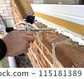 Window installation. The process of insulating windows with construction foam. A builder's hand seals the cracks between the building and the window frame. Construction and insulation of the building. 115181389