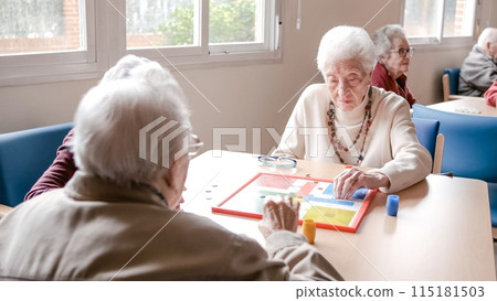 Senior woman playing ludo with friends at table in nursing home 115181503
