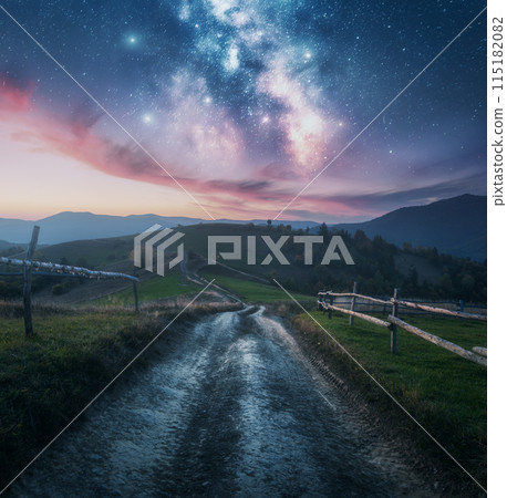 Milky Way, rural road, fence, green hills in mountains at night 115182082