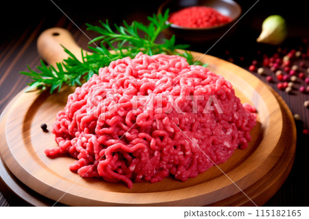 Fresh raw ground beef on a wooden cutting board with herbs and spices, perfect for recipes and culinary uses 115182165