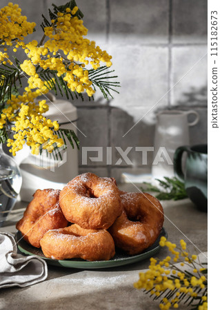 Delicious homemade crumpets or fried donuts sprinkled with powdered sugar on gray tile kitchen background in hard light 115182673