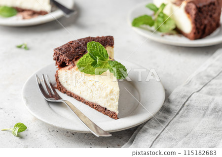 Piece of homemade chocolate cheesecake with mint leave on a plate on white textured background Piece of homemade chocolate cheesecake with mint leave on a plate on white textured background 115182683