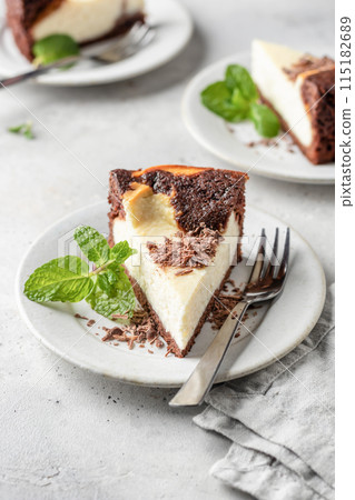 Piece of homemade chocolate cheesecake topped with chocolate chips mint leave on a plate on white textured background Piece of homemade chocolate cheesecake topped with chocolate chips mint leave on a plate on white textured background 115182689