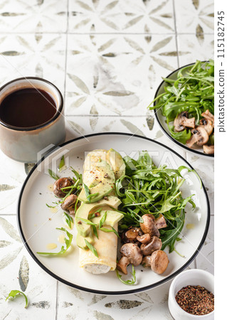 French rolled omelette stuffed with cream cheese with avocado, aragula and mushrooms for breakfast on white plate printed tile background French rolled omelette stuffed with cream cheese with avocado, aragula and mushrooms for breakfast on white plate printed tile background 115182745