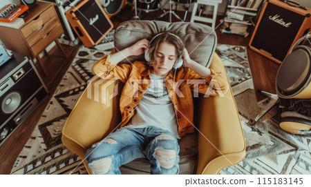 Hipster Teenager Relaxing with Headphones in Stylish Room, Enjoying Music or Podcast 115183145