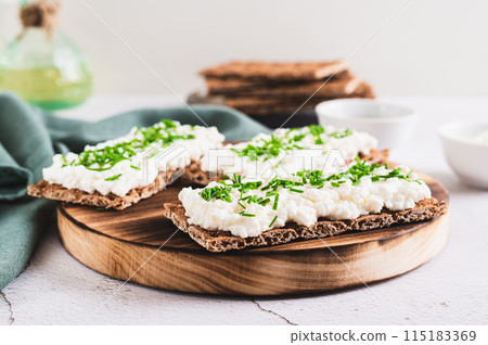 Homemade crispy rye toasts with ricotta and herbs on a board 115183369