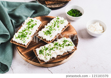 Homemade crispy rye bread with cottage cheese and green onions on a board 115183370