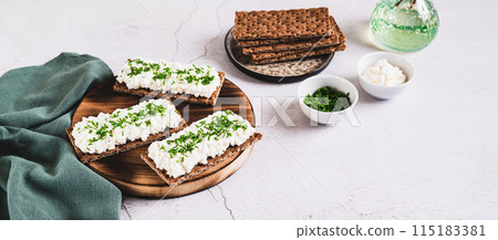 Homemade crispy rye toasts with ricotta and herbs on a board web banner 115183381