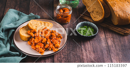 Baked beans with vegetables and rye bread on a plate on the table web banner 115183397