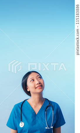 Curious doctor. Medical advertising. Cheerful smiling physician woman in uniform with stethoscope looking up isolated on blue empty space background. 115183886