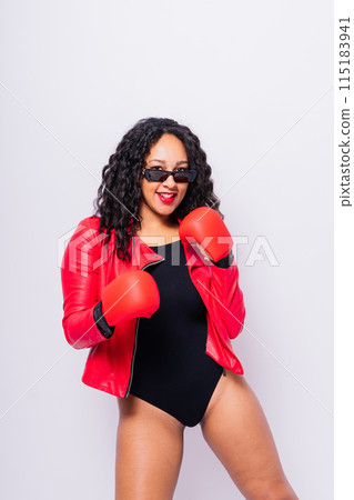 A beautiful young woman wearing a pair of boxing gloves A beautiful young woman wearing a pair of boxing gloves 115183941