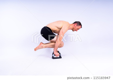 Shirtless muscular athlete doing push-up on push up bars. Full body man on white studio background. Shirtless muscular athlete doing push-up on push up bars. Full body man on white studio background. 115183947