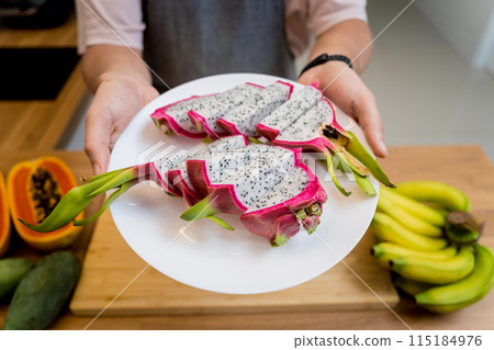Chef cuts and peels dragon fruit on the cutting board 115184976