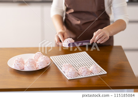 A woman is cutting a dessert on a wooden table A woman is cutting a dessert on a wooden table 115185084