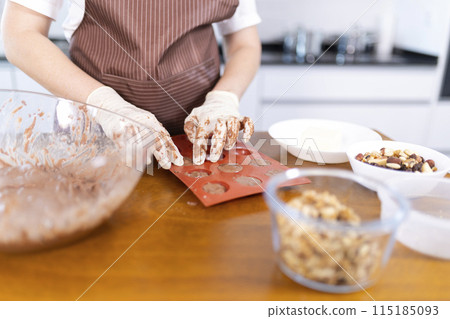 A woman is making cookies on a wooden table A woman is making cookies on a wooden table 115185093