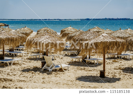 Straw umbrellas at beach. No people, beach with parasols, summer vacation concept 115185138