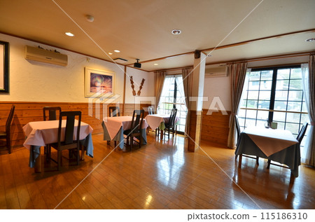A bright cafe-style dining room with morning sunlight streaming in 115186310