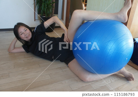 Tall woman riding a balance ball Tall woman riding a balance ball 115186793