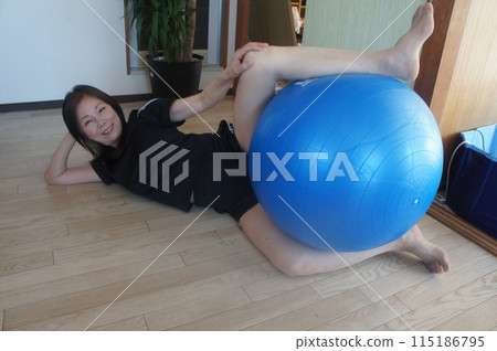 Tall woman riding a balance ball Tall woman riding a balance ball 115186795