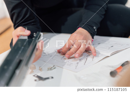 Hands of a woman assembling a piece of furniture following instructions at home Hands of a woman assembling a piece of furniture following instructions at home 115187105
