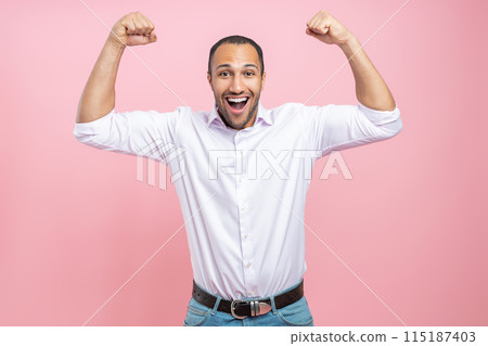 Excited man in white shirt showing his power with raised arms Excited man in white shirt showing his power with raised arms 115187403
