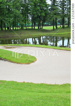 A golf course in lush early summer: a pond, a bunker, and an empty green A golf course in lush early summer: a pond, a bunker, and an empty green 115187490
