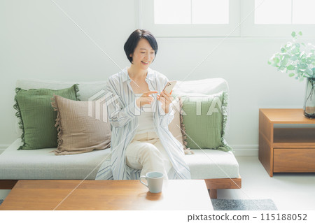 Middle-aged woman looking at her smartphone at home Middle-aged woman looking at her smartphone at home 115188052